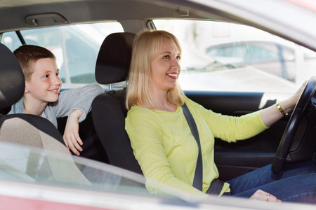 Smiling happy cheerful mother and son using car during sightseeing tour