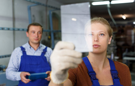 Experienced young workwoman working with glass in industrial workshop