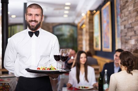 Portrait of smiling waiter with serving tray in the restaurantの写真素材