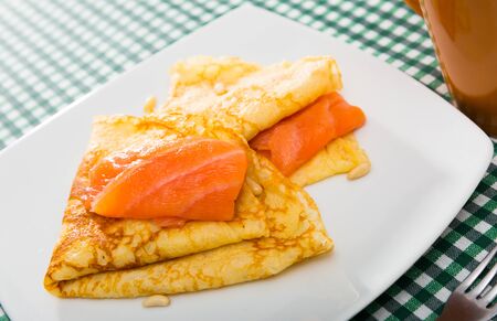 Tasty crepes with slice of smoked salmon served on white plateの写真素材