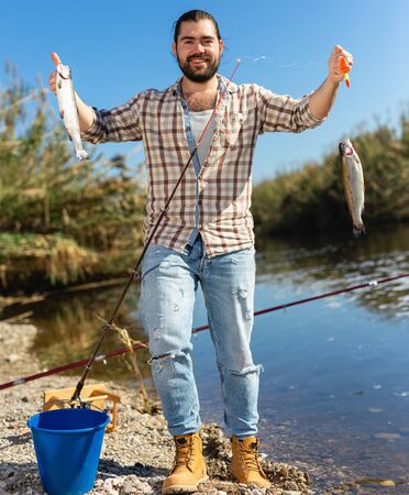 Positive fisherman holding catch freshwater fish in handsの写真素材