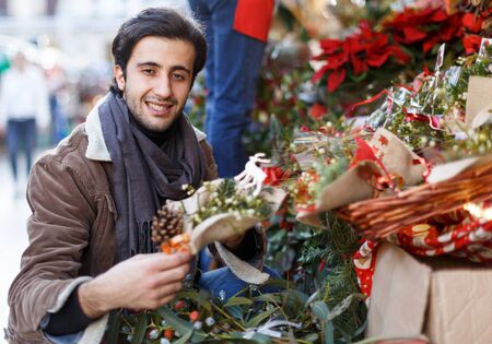Portrait of smiling young man with Christmas toys at fair outsideの写真素材