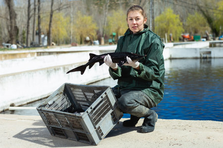 Portrait of successful female owner of sturgeon farm showing freshly caught fish outdoors