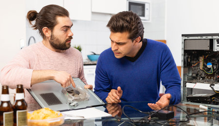 Two men repairing a desktop computer and drink beer