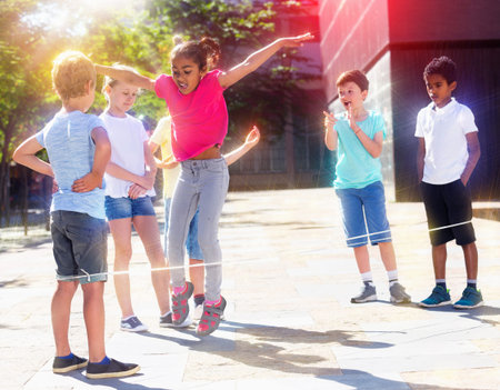 Happy smiling little friends playing with chinese jumping rope at playgroundの写真素材