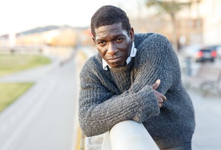 Portrait of cheerful African-American man in warm sweater in urban environmentの写真素材