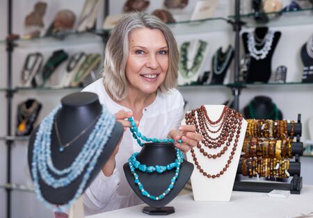 Woman trying on a turquoise necklace and earrings at a jewelry storeの写真素材