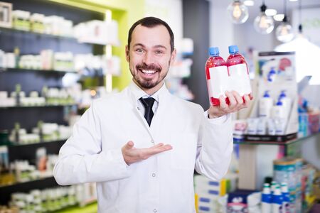 Cheerful pharmacist suggesting useful drug in pharmacyの写真素材