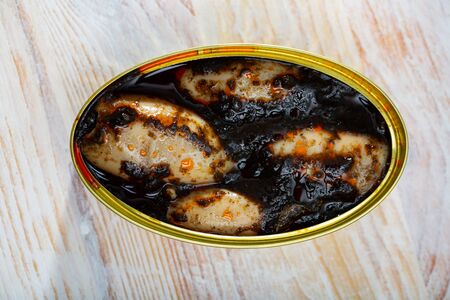 Open can with squid in ink on wooden tableの写真素材