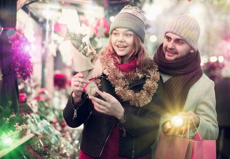 Portrait of joyful girl and boy choosing  toys and Christmas tree at fairの写真素材