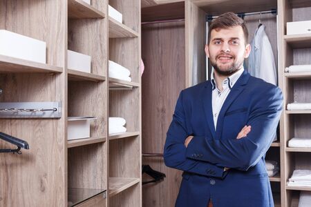 Portrait of young successful confident sales manager standing in interior of dressing room in furniture salonの写真素材