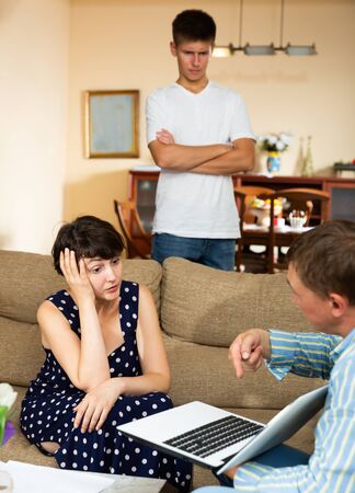 Upset woman and her son are talking to the collectorの写真素材