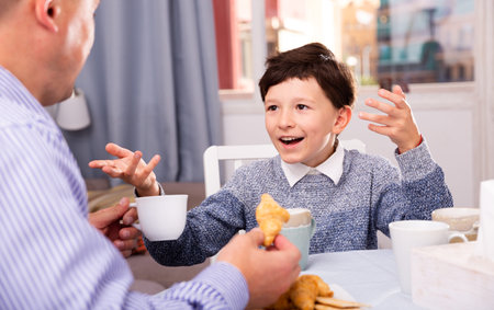 Portrait of happy preteen boy having friendly chat with his dad at homeの写真素材