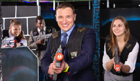 Man in the business suit holding a his laser gun and playing laser tag with colleaguesの写真素材