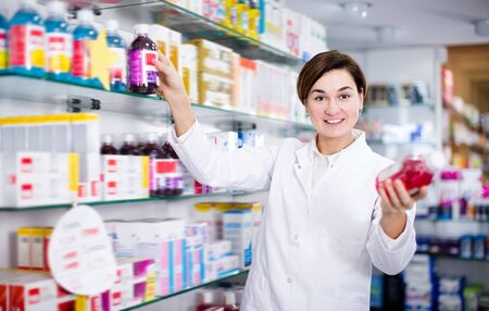 Happy pharmacist offering reliable medicine in pharmacyの写真素材