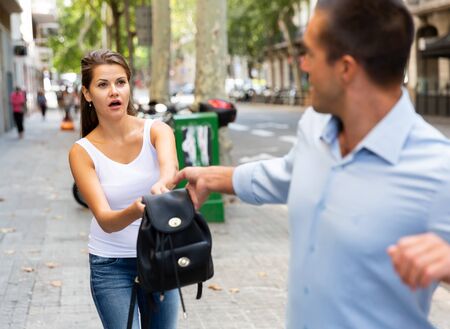 Man street robbery pulling woman backpack on streetの写真素材