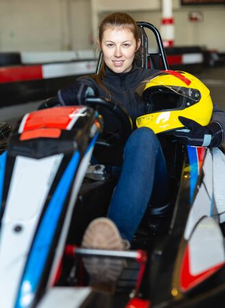 Portrait of female racer holding the helmet in her hand on kart trackの写真素材