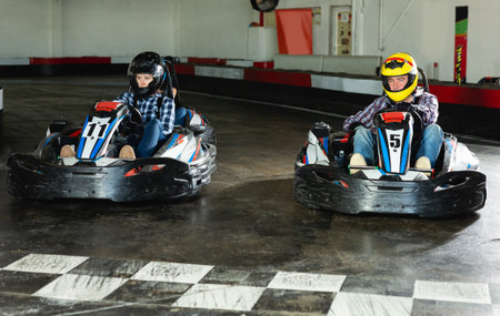active young  man and women competing on racing cars at kart circuit
