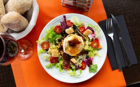 Salad from goat cheese with lettuce, meat, tomatoes and honey, dish of french cuisineの写真素材