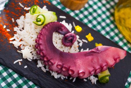 Slate of appetizing boiled octopus with rice garnish served on slateの写真素材