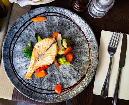 Tasty fish dish â€“ salmon in sauce served with blanched vegetables on plate