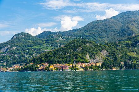 Spectacular view of Italian city of Varenna at foot of mountain on shore of Lake Como overlooking bell tower of Church of San Giorgio, Lombardyの写真素材