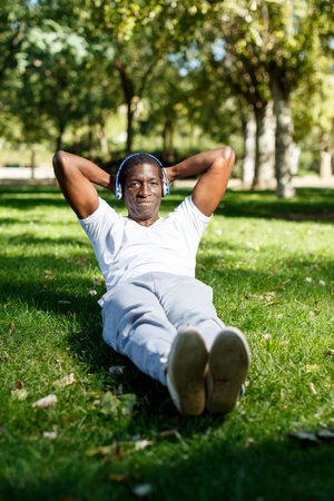 Athletic young male training exercises for legs and other at park outdoor
