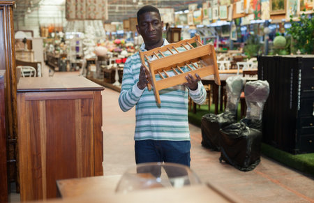 African American designer visiting furnishing store in search of stylish wooden pieces of furniture for home interiorの写真素材