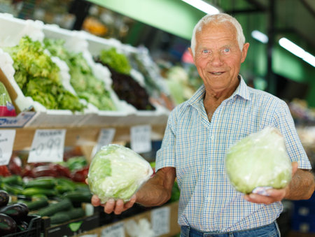 Senior man searching for fresh vegetables while shopping in greengroceryの写真素材