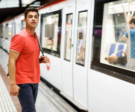 Man is standing on platform and running into trainの写真素材