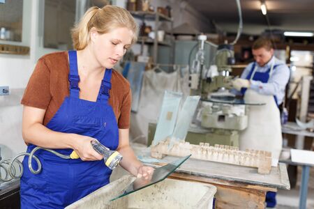 Experienced female worker cleaning cut glass in industrial workshopの写真素材