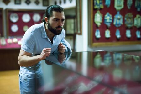 Adult man looking at exhibits in glazed stands in historical museumの写真素材