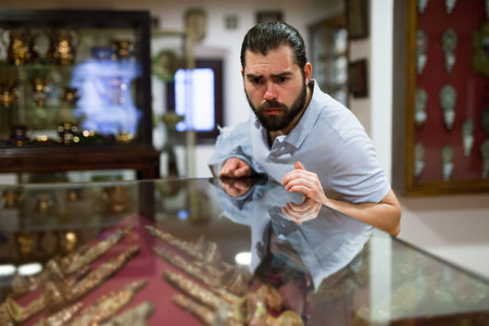 Adult man looking at exhibits in glazed stands in historical museum