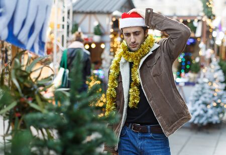 Portrait of joyful  man choosing toys and Christmas tree at fair outdoorの写真素材