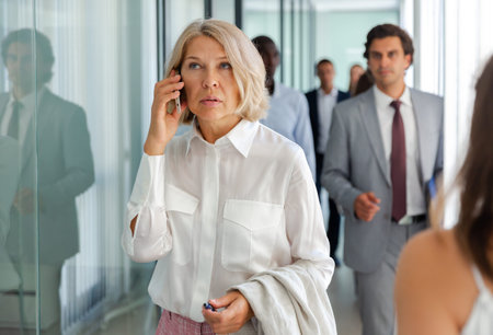 Portrait of adult business woman talking on mobile phone in office