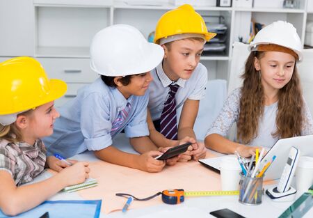 Group of children in helmet talking about building near laptopの写真素材