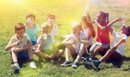 Children drink water from plastic bottles after playing footballの写真素材