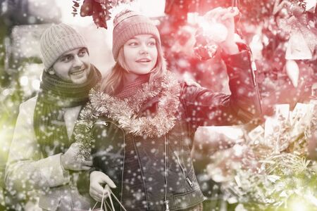 Smiling girl with boy choosing decorations at Christmas marketの写真素材