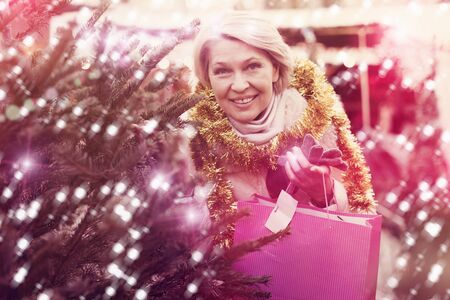 Woman is preparing for Christmas and choosing X-mas tree outdoor.の写真素材