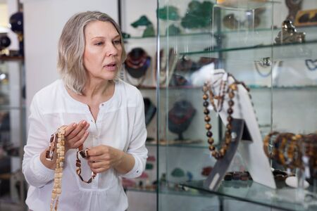 Adult woman chooses jewelry from gemstone jewelery in the storeの写真素材