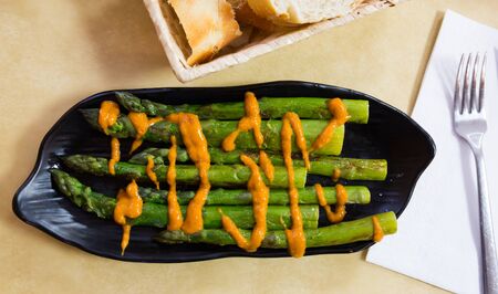 Top view of grilled green asparagus served with romesco sauce on black plate. Catalan cuisineの写真素材