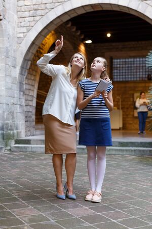Portrait of young woman with daughter using guide and walking near museum of  history arts  outdoorの写真素材