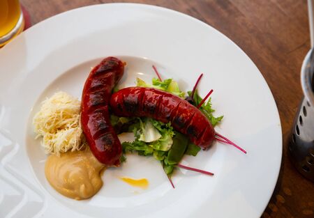 Appetizing grilled sausages with lettuce, sauce and grated cheeseの写真素材
