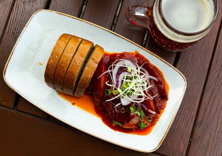Traditional Czech beer snack - Baked sausages with red onion and breadの写真素材