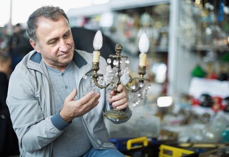 Senior man customer choosing vintage souvenir at flea marketの写真素材