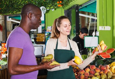 Man client is asking from seller female about freshness fruits in the marketの写真素材