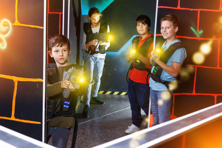 Group of happy cheerful glad teenagers with laser guns having fun on dark lasertag arenaの写真素材