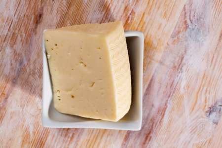 Cut piece of fresh cow cheese on wooden background