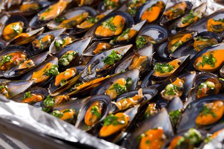 Freshly baked black shell mussels with herbs in oven trayの写真素材