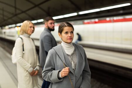 Young woman waiting for subway train at modern underground stationの写真素材